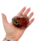 Rhodonite polished free form from Zimbabwe held in hand to show scale
