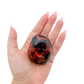 Rhodonite polished free form from Zimbabwe held in hand to show scale