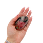Rhodonite polished free form from Zimbabwe held in hand to show scale