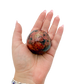 Rhodonite polished free form from Zimbabwe held in hand to show scale