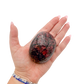 Rhodonite polished free form from Zimbabwe held in hand to show scale