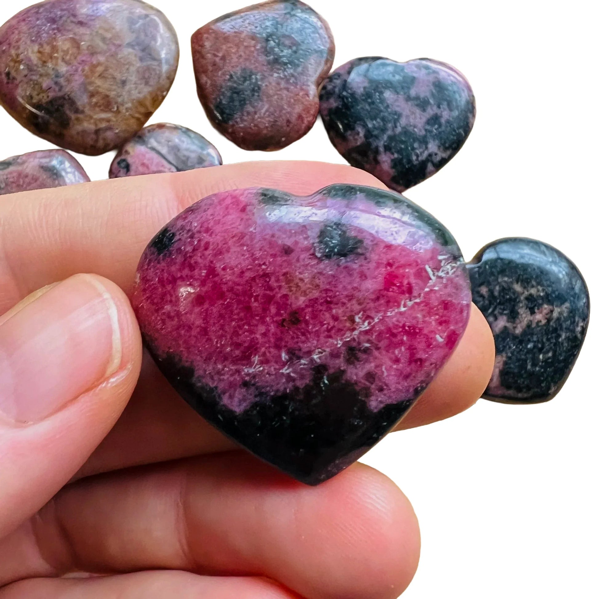 Size comparison with a single Rhodonite polished heart sourced from Madagascar.