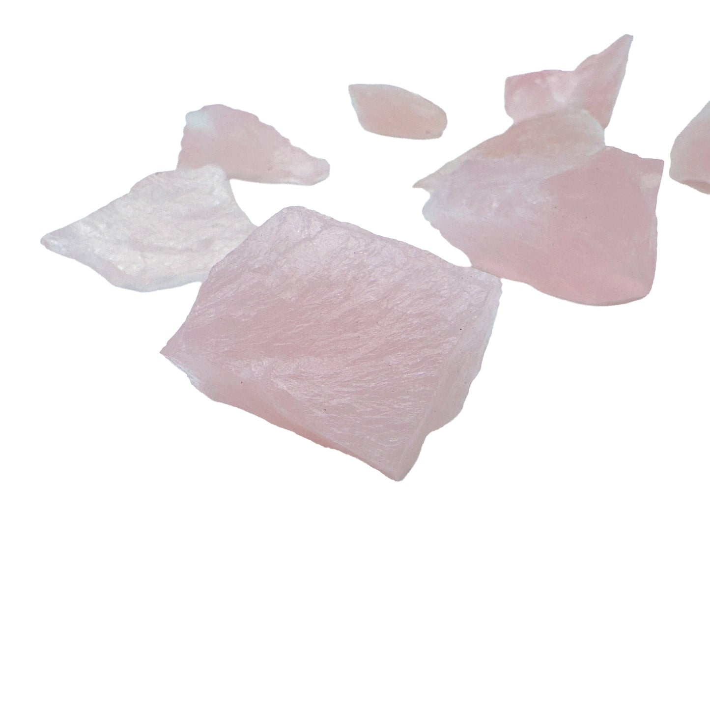 Size variation across several Rose Quartz pieces, with flatter translucent slabs beside thicker blocky chunks.