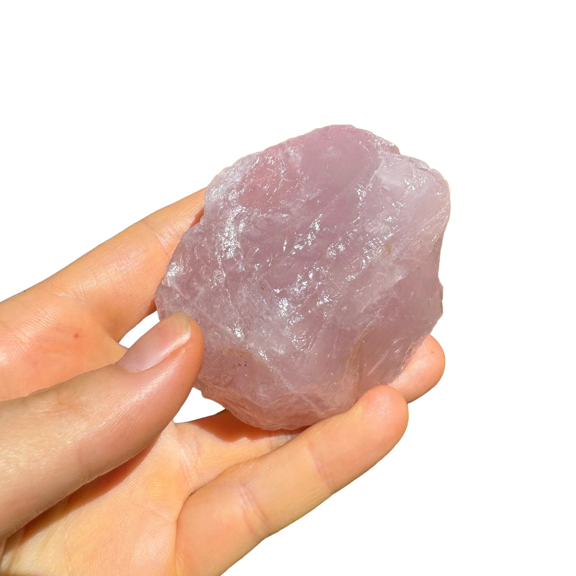 Hand-scale view of Rose Quartz specimen, set against a soft neutral surface.