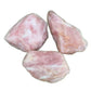 Natural light view of a Rose Quartz raw stone held against natural backdrop.