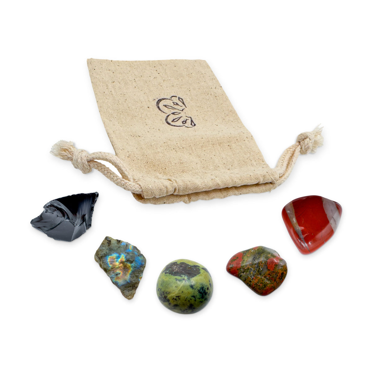 Scorpio Crystal Kit: black obsidian, labradorite, serpentine, unakite and red jasper, arranged with the reusable cotton bag they come in, on white