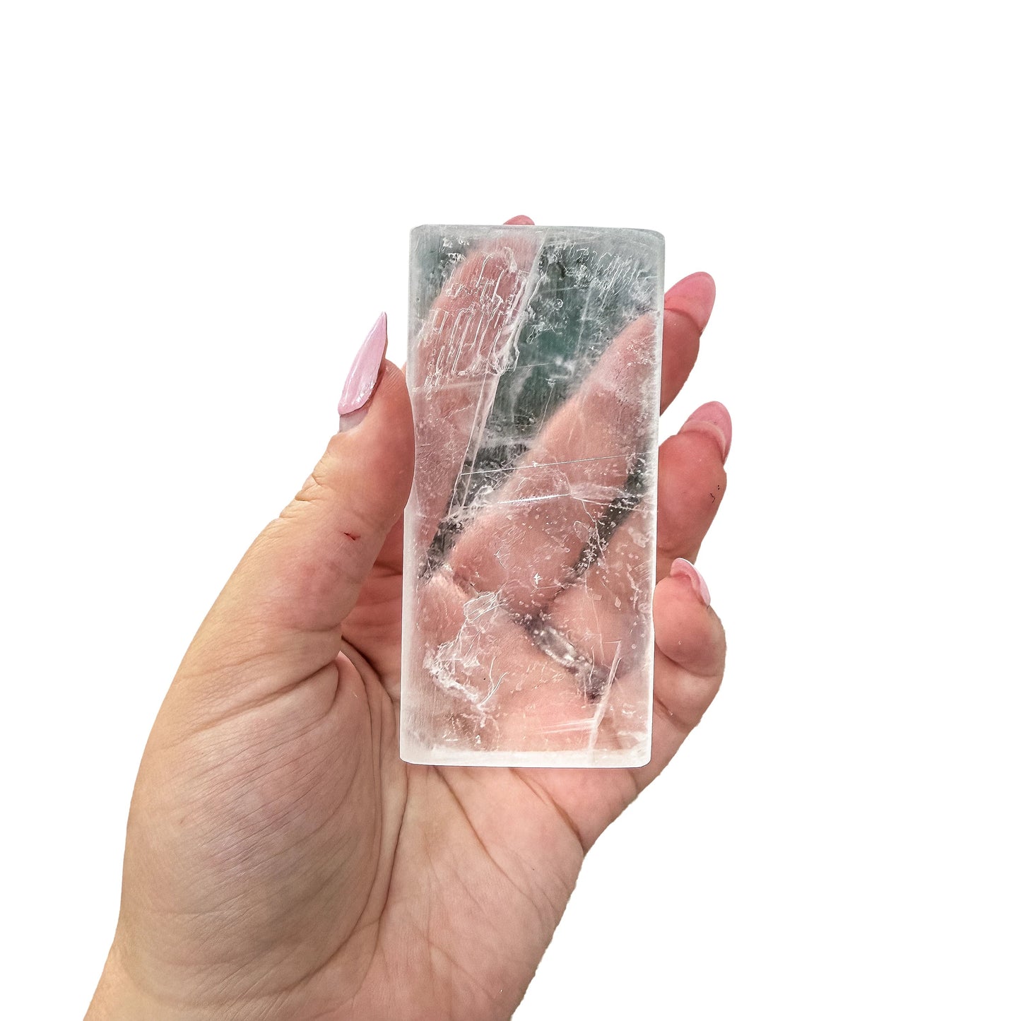 A Selenite polished stick held up outdoors with light passing through it