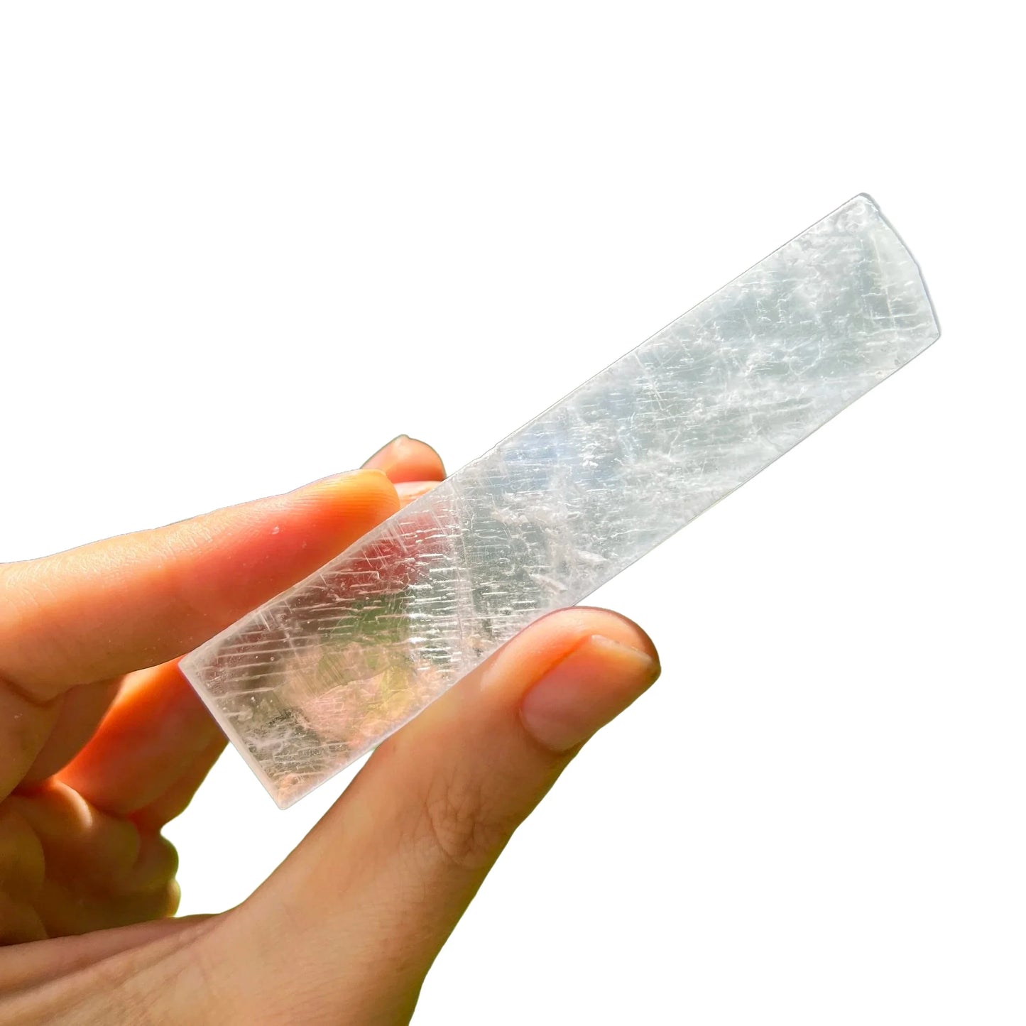 Hand-held view of a Selenite raw stone held against natural backdrop, sourced from New Mexico, USA.
