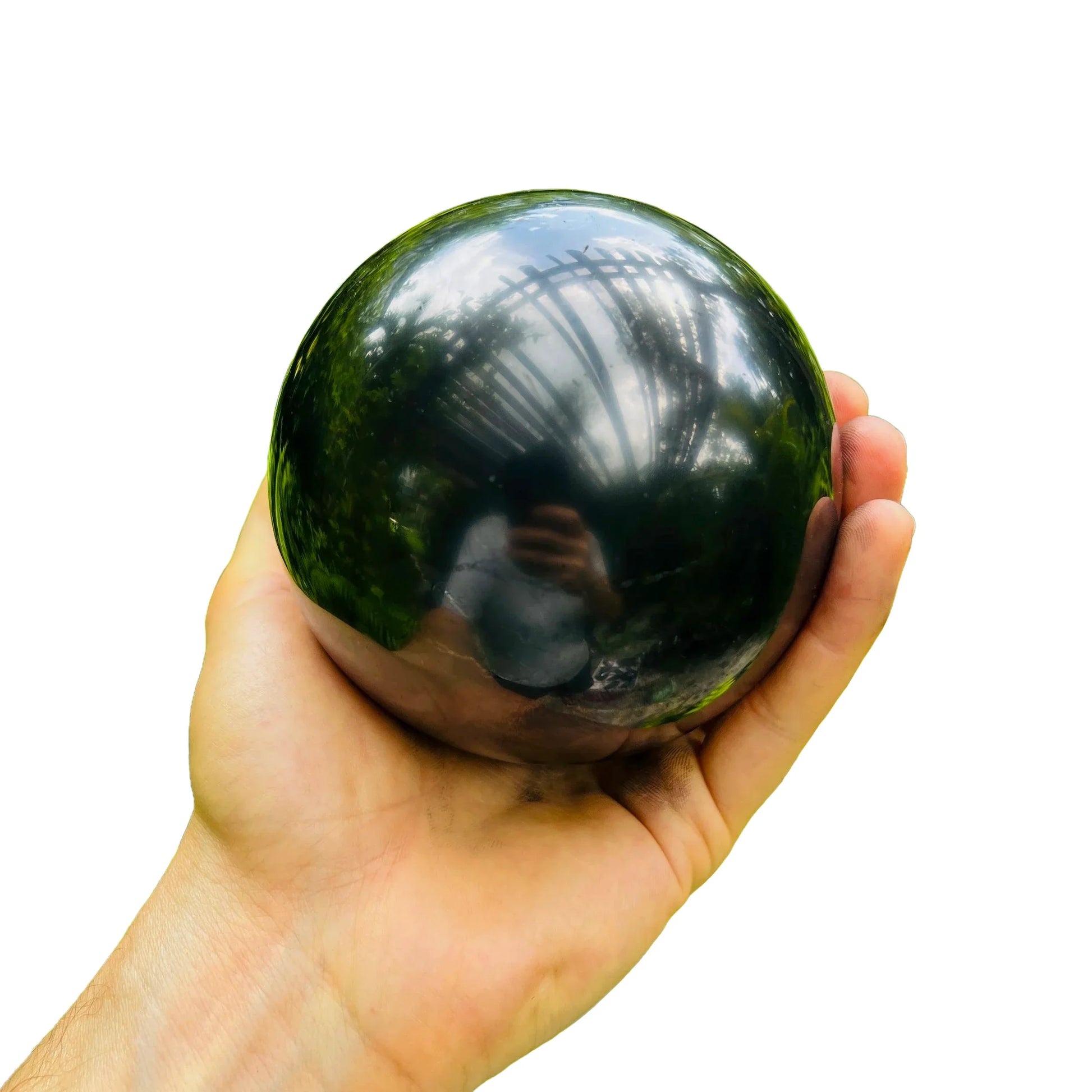 Size comparison with a Shungite polished sphere held against natural backdrop.