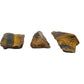 Three raw Tiger Eye stones lined up on white, each showing a different mix of gold banding and dark blue-grey unaltered crocidolite.